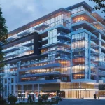 Modern glass facade exterior rendering of the Distrikt Trailside condominium building at dusk, showcasing illuminated multi-story balconies and street-level entrance.