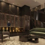 Luxury condo lobby interior at Distrikt Trailside featuring a prominent golden concierge desk, a plush green velvet sofa, and a dramatic black spiral staircase.
