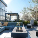 Outdoor rooftop terrace lounge at Distrikt Trailside featuring comfortable sectional patio seating, a central concrete fire pit table, and scenic landscaping with blossoming trees.