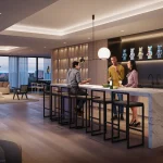 The spacious party room amenity at Arte Residences, showcasing a long marble island with bar stools, modern lighting, and residents socializing in a chic lounge area.