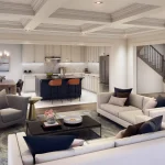Interior view of an open-concept great room at Caledon Trails, showcasing a coffered ceiling, modern fireplace, luxury living area, and a gourmet kitchen with a dark blue island.