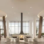 Spacious residents' lounge at Alba Condos featuring a central modern fireplace, plush armchairs, floor-to-ceiling windows, and decorative wood pillars.