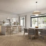 Modern open-concept kitchen and dining area at Union Village featuring light wood herringbone floors and a large island.