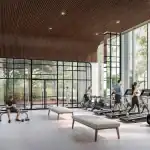 The state-of-the-art fitness center at The Greenwich with floor-to-ceiling windows, modern treadmills, weight lifting equipment, and a unique architectural wood-paneled curved ceiling.