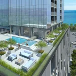 Outdoor rooftop amenity deck at Nautique Lakefront Residences featuring an outdoor swimming pool, lounge seating, a fire pit, and expansive views of the blue lake.