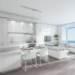 Bright, modern open-concept condo interior at Nautique Lakefront Residences, featuring a white kitchen, dining island, living room, and floor-to-ceiling windows with a lake view.
