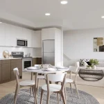 Open-concept modern kitchen and living room featuring white upper cabinets, stainless steel appliances, dining table, and cream sectional sofa at Marquis Modern Towns