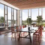 Sun-drenched co-working space at The Kith Condominiums with long communal tables, individual desks, and floor-to-ceiling windows.