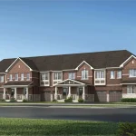Architectural rendering of traditional two-storey townhomes in the Seaton Whitevale community, featuring red brick exteriors, white window trim, peaked gables, covered front porches, and built-in garages under a clear blue sky.