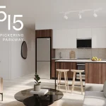 Modern open-concept suite interior at 1515 Pickering Parkway showing a contemporary kitchen with wood and white cabinetry, stainless steel appliances, a kitchen island with seating, and a bright living area.