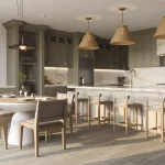 Modern open-concept kitchen interior at Caledon Club, showcasing olive green cabinetry, a large white marble island with seating, woven pendant lights, and an adjacent round dining table.