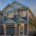 Modern two-story Colorado detached home model in the Aster community, showcasing dark blue horizontal siding, light grey accents, a stone-veneer garage facade, and a glowing twilight sky.