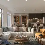 Interior view of a Wild Indigo townhome featuring a ribbed white sectional sofa, dark wood kitchen cabinetry with a marble backsplash, and large windows overlooking a backyard.