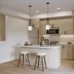Modern open-concept kitchen at East Hills Crossing featuring light wood cabinetry, a white quartz waterfall island with seating, stainless steel appliances, and contemporary globe pendant lighting.