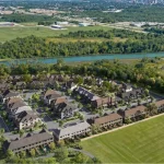 Birds-eye aerial rendering of the completed Wellwood residential community development situated beside a river and natural greenery.