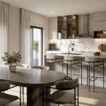 Modern open-concept kitchen and dining area at 180 Towns featuring a marble waterfall island, gold hardware, integrated appliances, and a large wooden dining table under natural light.