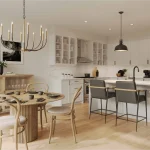 Modern open-concept kitchen and dining area at Heartwood Village featuring white cabinetry, a large island with breakfast seating, light wood flooring, and a contemporary chandelier over a round wooden dining table.