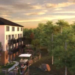 Exterior rendering of Riverbank Place townhomes at sunset, showcasing private balconies, fenced backyards with patio furniture, and lush green landscaping against a golden sky.