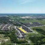 High-angle aerial view of the Sharon Village residential development, showing the master-planned community layout, surrounding green spaces, and a highlighted section of upcoming new home lots.