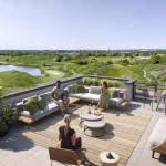 Rooftop terrace lounge area at Spruce Trails with outdoor furniture and a panoramic view overlooking the adjacent golf course greens and landscape.