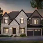 High-end residential architecture at The Legacy community, featuring a multi-gabled stone and brick exterior with large black-framed windows, a modern front door, and professional landscaping under a sunset sky.