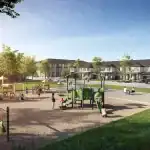 A vibrant community park at Wasaga Walk featuring a modern children's playground with slides and swings, surrounded by paved walking paths and contemporary townhomes in the background.