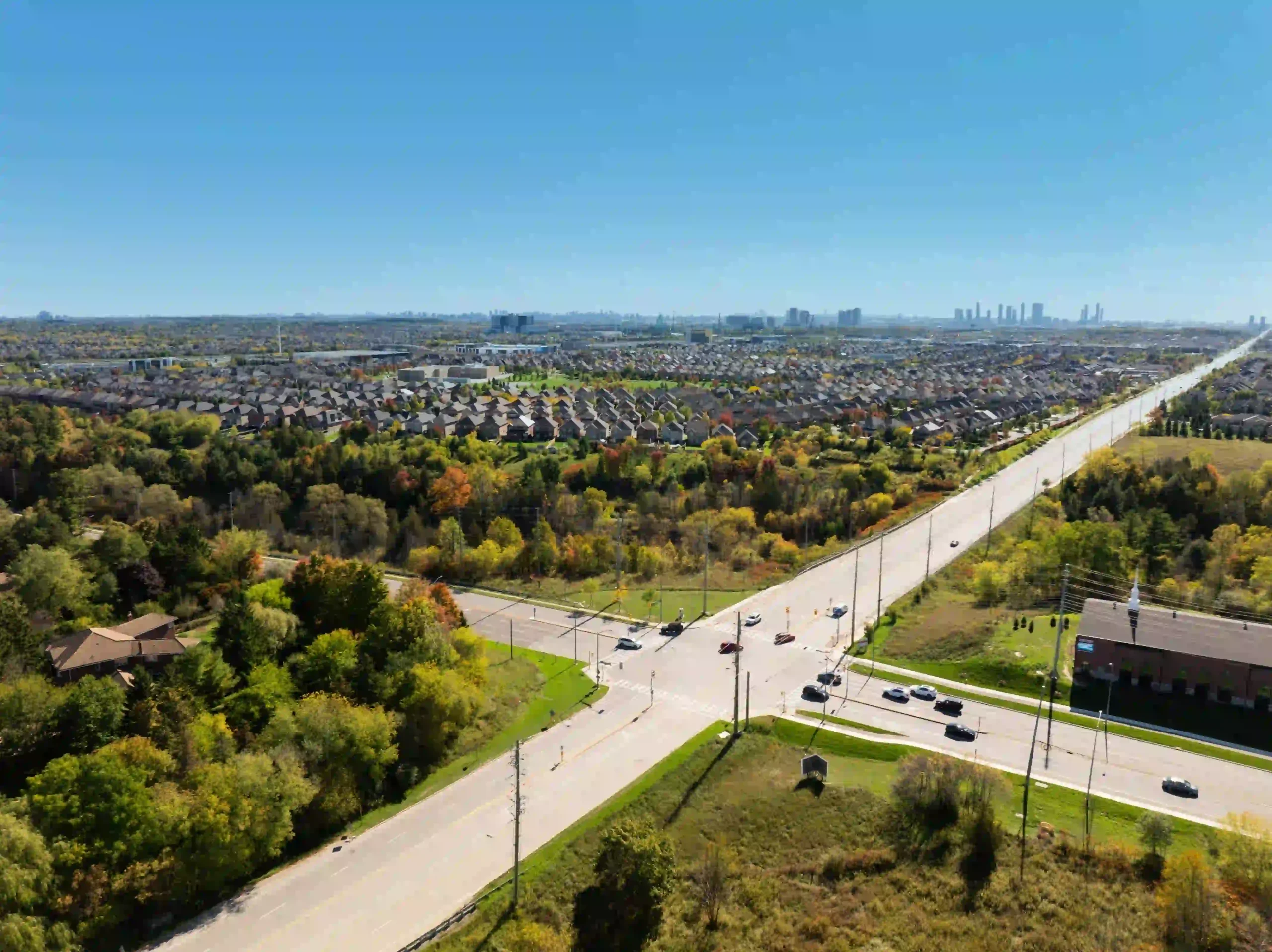 Aerial view of the Bridgelands residential neighborhood showing surrounding greenery, roadways with traffic, and distant city skyline views.