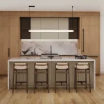 Modern open-concept kitchen at Wellington Place featuring warm wood cabinetry, a large marble island with four barstools, linear pendant lighting, and adjoining dining space.