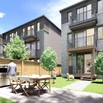 Fenced backyard patio of an Everpine townhouse featuring a stainless steel grill, wooden dining table, green lawn, and multi-level balconies.