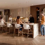 Modern open-concept luxury kitchen interior at Everstone by Cachet with a large marble waterfall island, gold pendant lighting, custom wood cabinetry, herringbone hardwood flooring, and people gathering.
