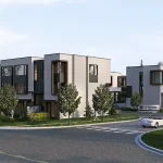 Streetscape view of modern multi-story townhomes at Le Sentier Towns featuring paved roads, cars, and green landscaping.