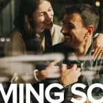 Smiling couple sitting together in a cafe with bold white text reading Coming Soon for Uptown Woodbridge by Fieldgate Homes.
