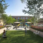 Outdoor community park and children's play area with playground equipment, landscaped flower beds, and green space at the Elements townhouse development.